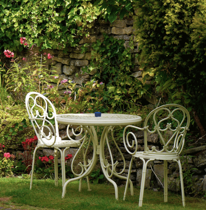 White metal outdoor furniture in a garden of green with various flowers.